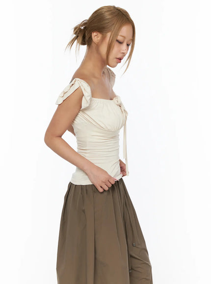 Ruched Off-Shoulder Bow Detail Top CU524 light beige side shot on model looking down showing shoulder bow tie ruched front panel and center ribbon