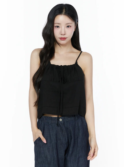 Ruched Ribbon Cami Top IU525 Black front crop shot on model showing gathered ruched neckline center ribbon tie and sheer paneled fabric styled with dark denim