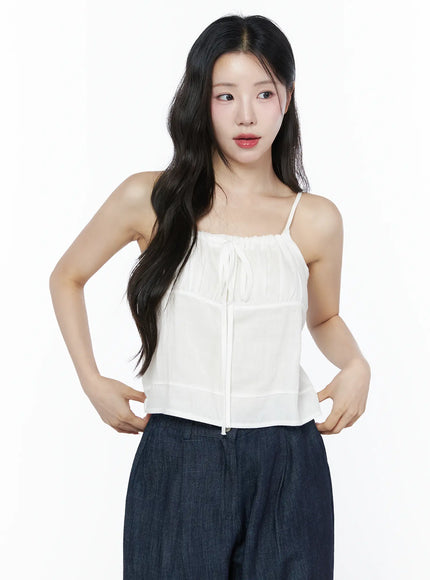 LEWKIN Ruched Ribbon Cami Top IU525 White S/M front crop shot on model hands on hips showing gathered neckline tie detail with sheer layered fabric