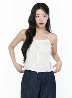 LEWKIN Ruched Ribbon Cami Top IU525 White S/M front crop shot on model hands on hips showing gathered neckline tie detail with sheer layered fabric