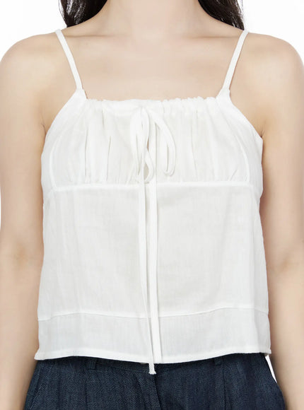Ruched Ribbon Cami Top IU525 White close-up front detail shot on model showing ruched gathered neckline center ribbon tie and sheer paneled fabric texture