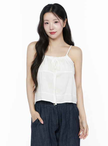 Ruched Ribbon Cami Top IU525 White front shot on model smiling with hand in pocket styled with dark navy wide-leg denim trousers cropped waist view