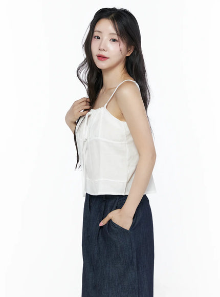 Ruched Ribbon Cami Top IU525 White side shot on model hand touching chest showing profile of gathered neckline ribbon tie and sheer layered hem detail