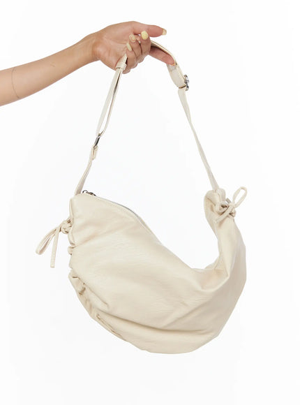 LEWKIN Ruched Shoulder Bag CL503 Light beige held by hand showing side profile with ruched leather body, bow tie details, and silver zipper