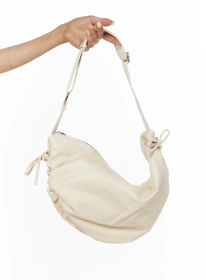 LEWKIN Ruched Shoulder Bag CL503 Light beige held by hand showing side profile with ruched leather body, bow tie details, and silver zipper