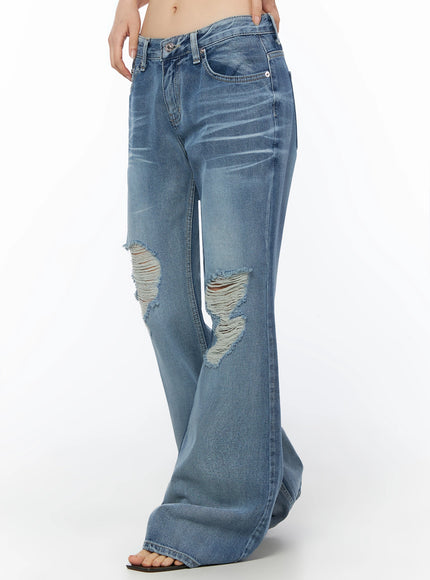 Rue Distressed Bootcut Flare Jeans IU525 Blue side crop shot on model highlighting low-rise fit, large frayed rip on left knee, and wide flare hem