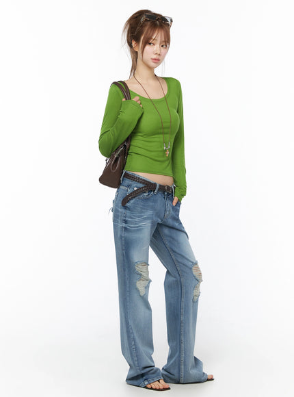 Rue Distressed Bootcut Flare Jeans IU525 Blue three-quarter view on model styled with green long-sleeve top, braided belt, and brown shoulder bag