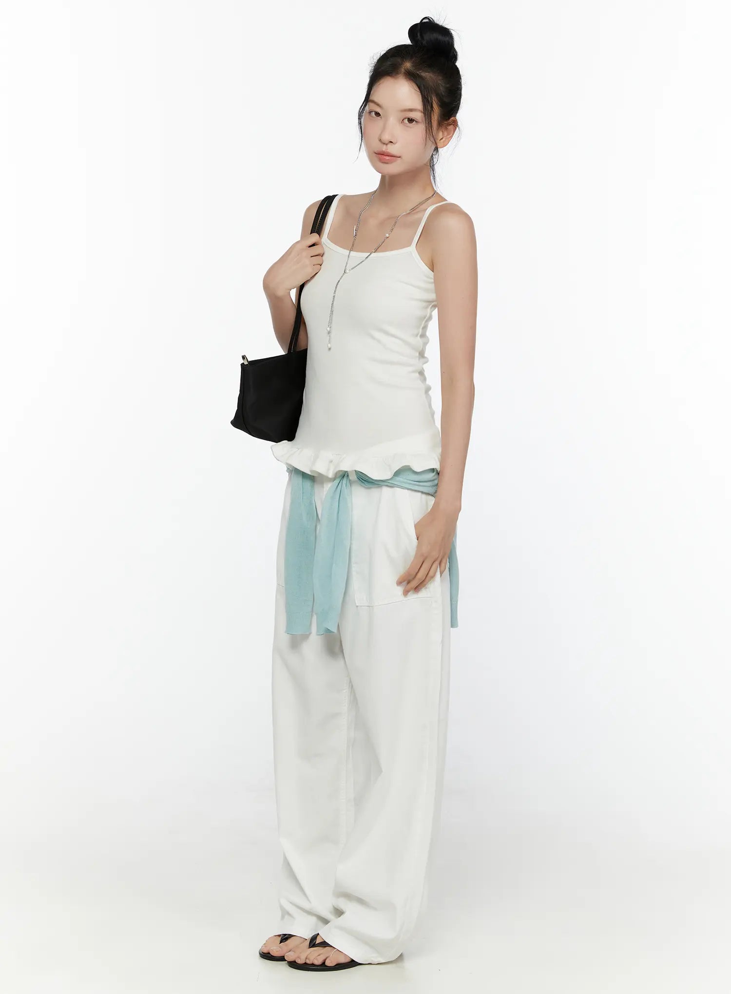 Ruffle Detail Cami Top CL521 White side shot on model full-length view, spaghetti straps, fitted ribbed silhouette, ruffle hem detail, styled with white wide-leg pants and black tote bag