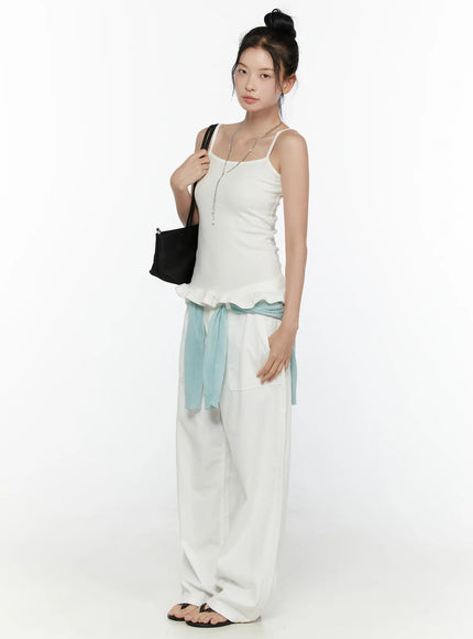 Ruffle Detail Cami Top CL521 White side shot on model full-length view, spaghetti straps, fitted ribbed silhouette, ruffle hem detail, styled with white wide-leg pants and black tote bag