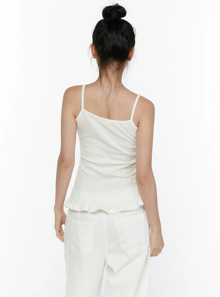 Ruffle Detail Cami Top CL521 White back shot on model, spaghetti straps crossing upper back, fitted ribbed knit back, ruffled hem detail at hip level, paired with white trousers