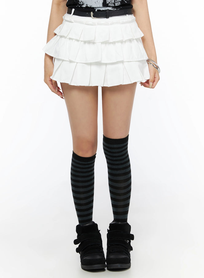LEWKIN Ruffle Detail Mini Skirt IL523 White front close-up on model wearing S size with black belt, three-tier pleated texture, styled with striped knee socks