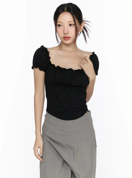 Ruffle Detailed Blouse CL527 Black front model shot with scalloped neckline, puff sleeves, center button detail, styled with gray wide-leg trousers