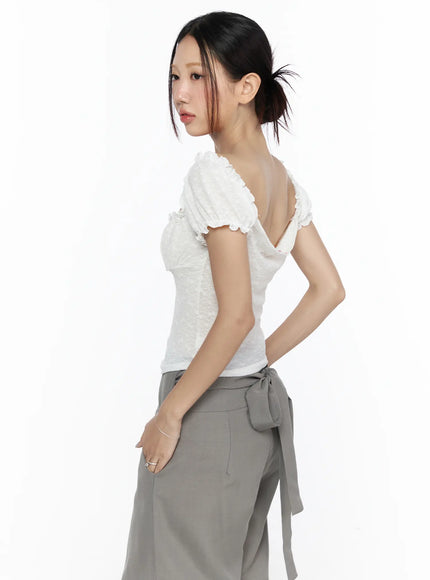 Ruffle Detailed Blouse CL527 White side-back model shot showing open back neckline and puff sleeve ruffles, model glancing over shoulder with ponytail
