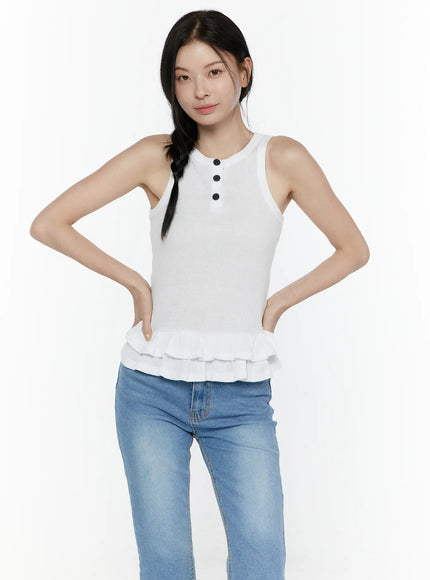 Ruffle Hem Tank Top IL506 White front shot on model with hands on hips, close-up view showing ribbed texture, three black buttons, and double tiered ruffle hem, styled with blue jeans