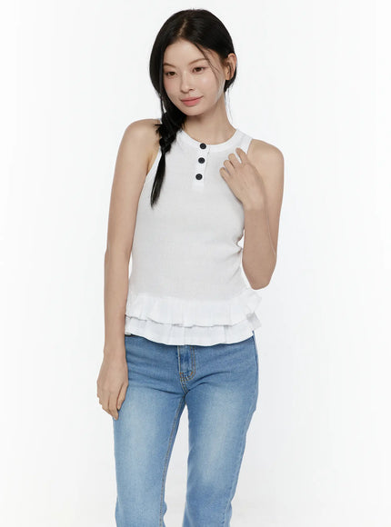 Ruffle Hem Tank Top IL506 White front shot on model smiling with hand to chest, ribbed sleeveless henley top with three black buttons and double ruffle hem, styled with blue jeans