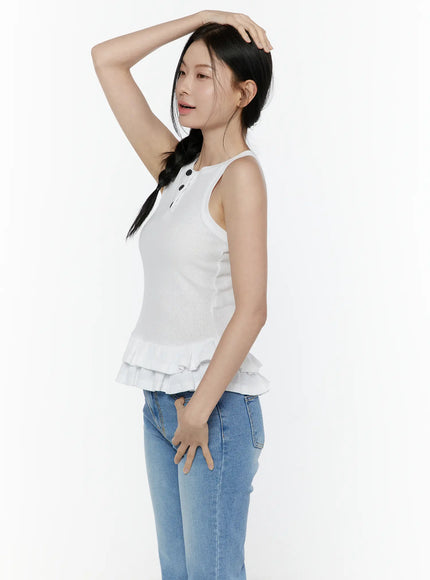 Ruffle Hem Tank Top IL506 White side shot on model with hand raised to head, showing silhouette of ribbed sleeveless top with tiered ruffle hem, paired with blue jeans