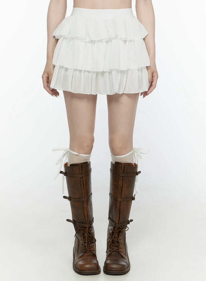 LEWKIN Ruffle Layered Mini Skirt IL521 White front view on model wearing brown combat boots and sheer socks, S/M, pleated three-tier mini skirt