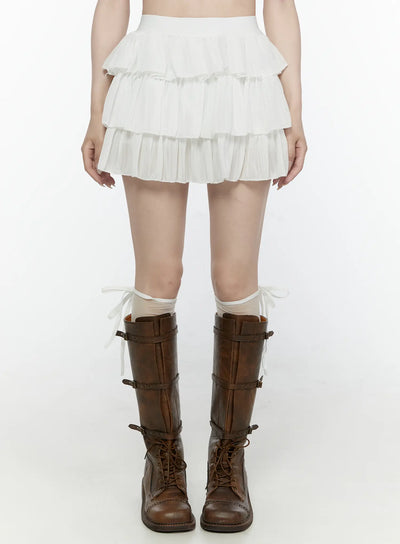 LEWKIN Ruffle Layered Mini Skirt IL521 White front view on model wearing brown combat boots and sheer socks, S/M, pleated three-tier mini skirt