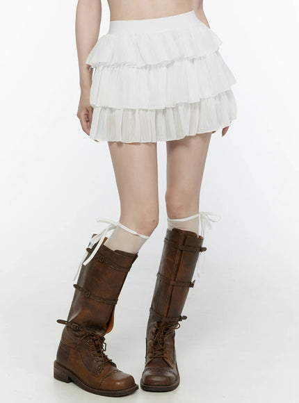 Ruffle Layered Mini Skirt IL521 White front detail view on model showing pleated ruffle tiers and elastic waistband, styled with brown buckle boots