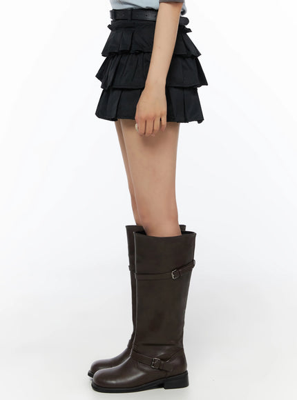 Ruffle Layered Mini Skirt IL523 Black side model crop shot showing layered pleated tiers and belt detail at waist paired with dark knee-high boots