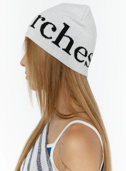 Sawyer Marches Beanie IL503 white side-rear view on model showing black intarsia script lettering wrapping around knit beanie
