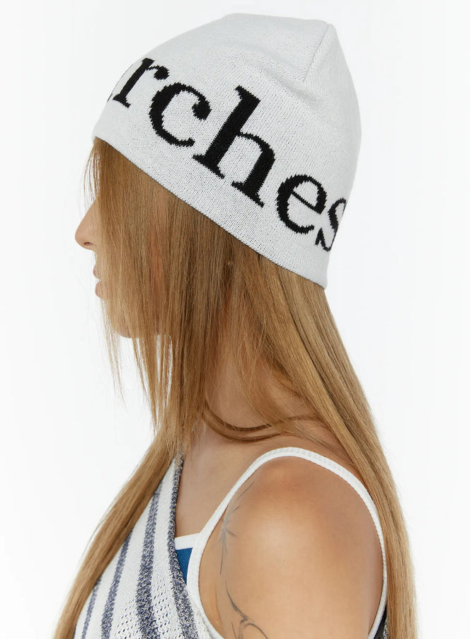 Sawyer Marches Beanie IL503 white side-rear view on model showing black intarsia script lettering wrapping around knit beanie
