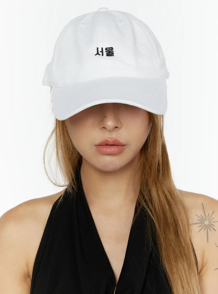 Seoul Mood Cap IL503 White front view on model with brim pulled low over eyes, black halter styling, structured cotton crown with Seoul Hangul embroidery