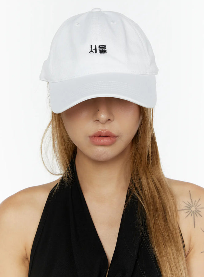 Seoul Mood Cap IL503 White front view on model with brim pulled low over eyes, black halter styling, structured cotton crown with Seoul Hangul embroidery