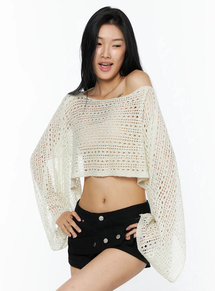Shawl Crop Knit Top IL506 Light beige front model hands on hips highlighting wide batwing sleeves open-knit crochet texture and cropped midriff-baring hem