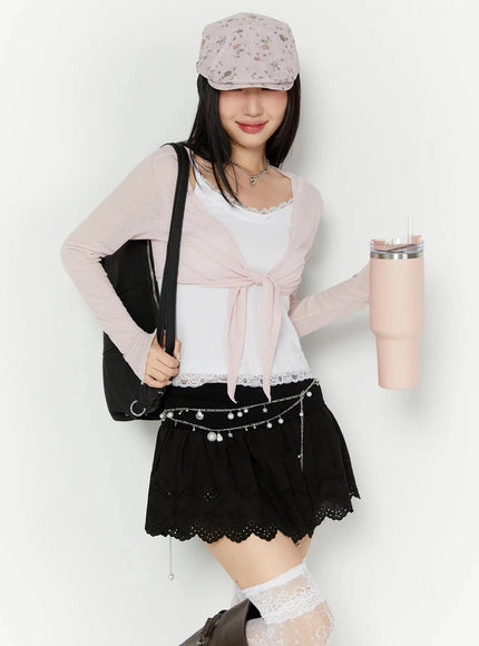LEWKIN Sheer Front-Tie Wrap Cardigan IU524 Pink S/M front shot on model styled with black eyelet mini skirt, floral cap, and black backpack
