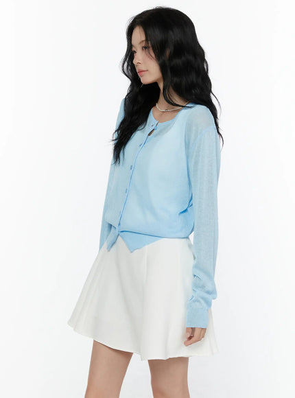 Sheer Knit Cropped Cardigan CL520 Light blue side-angle shot on model looking down showing sheer knit texture and scalloped cropped hemline