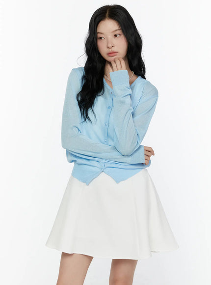 Sheer Knit Cropped Cardigan CL520 Light blue three-quarter shot on model hand raised to chin showing sheer sleeves and wavy hemline