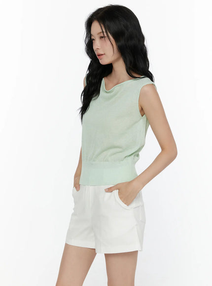 Sheer Knit Sleeveless Top CL521 Green side shot on model looking down hand in pocket styled with white shorts showing mint green sheer knit texture