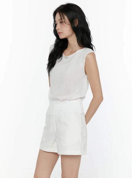 Sheer Knit Sleeveless Top CL521 White side-angle shot on model looking down hand in pocket showing ribbed hem and sheer knit fabric without accessories