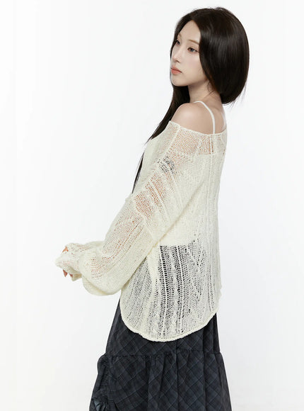 Sheer Knit Top IL522 Light beige three-quarter side shot on model glancing back showing sheer open-knit texture sleeve detail and off-shoulder spaghetti strap over dark skirt