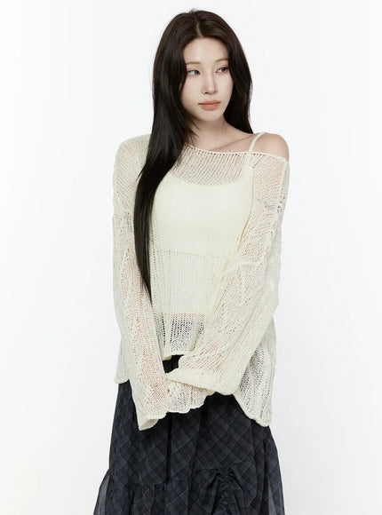 Sheer Knit Top IL522 Light beige front crop shot on model with slight downward gaze showing off-shoulder neckline open-knit semi-transparent fabric and long sleeves over dark plaid skirt