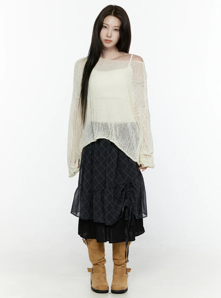 Sheer Knit Top IL522 Light beige full-body front shot on model standing straight wearing off-shoulder open-knit top layered with plaid midi skirt and tan knee-high boots