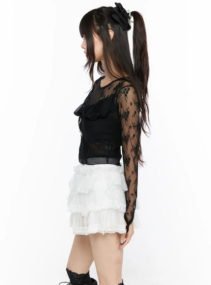 Sheer Lace Ribbon Tank CL522 Black left side view on model with twintail hair, highlighting sheer lace sleeve texture and ruffle bib detail with ribbon bows