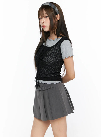 Sheer Lace Ribbon Tank Top CL514 Black side-angle three-quarter view on model layered over gray tee with gray ruffle-waist pleated mini skirt showing lace texture ribbon drawstring detail
