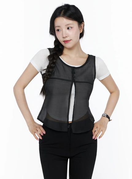 Sheer Layered Blouse IU525 Black front model shot, model hands on hips, sheer mesh vest with black trim and button front over white tee and black pants