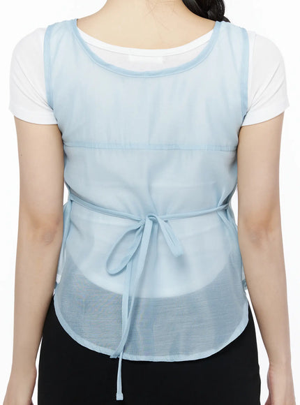 Sheer Layered Blouse IU525 Light blue upper-body close-up front detail, model looking down smiling, semi-transparent chiffon with front button closure and empire seam