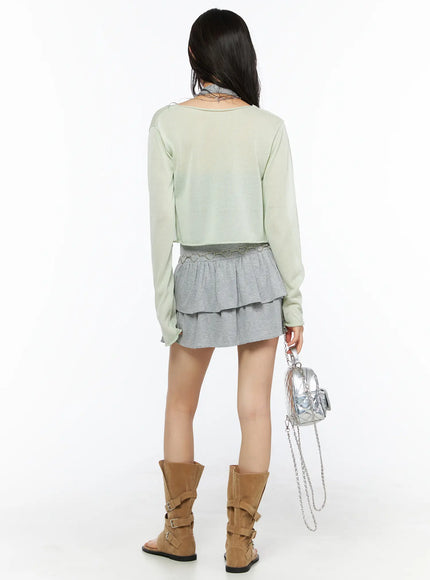 Sheer Lightweight Knit Cardigan CU530 Light green back view on model with tan suede boots and silver mini bag showing heart chain belt detail on gray tiered ruffle skirt