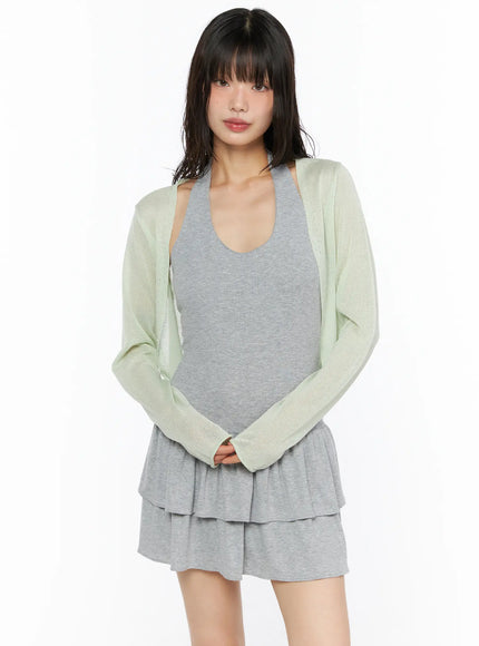 Sheer Lightweight Knit Cardigan CU530 Light green front view on model standing with hands clasped showing open-front silhouette over gray layered ruffle mini dress