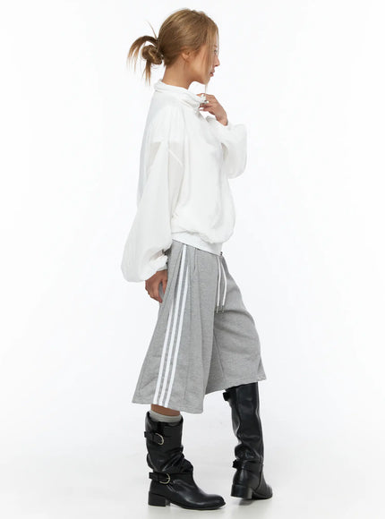 Sheer Nylon Windbreaker CU523 White side shot on model in ponytail showing balloon sleeves and elastic hem with gray stripe wide-leg pants and boots