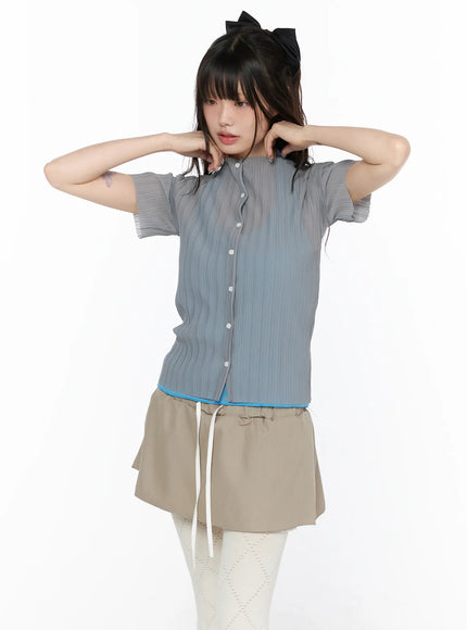 Sheer Pleated Short Sleeve Cardigan CL523 grey front view on model hands raised behind neck layered over blue cami with beige mini skirt