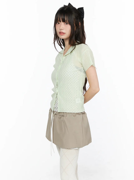 Sheer Pleated Short Sleeve Cardigan CL523 Light green angled side view on model showing open-front collar dot-jacquard body and brand label patch at hem