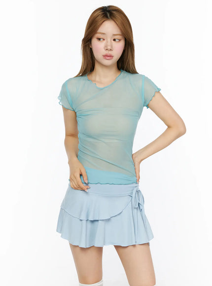 Sheer Short Sleeve Top CL501 mint front model shot, sheer ruched mesh tee with lettuce-edge neckline and sleeves, paired with light blue tiered ruffle mini skirt, hand on hip