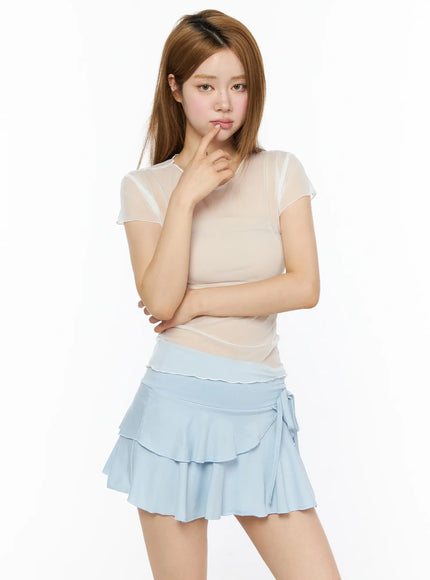 LEWKIN Sheer Short Sleeve Top CL501 White S/M front model shot, sheer mesh short sleeve top with lettuce hem, styled with light blue tiered mini skirt, thoughtful pose