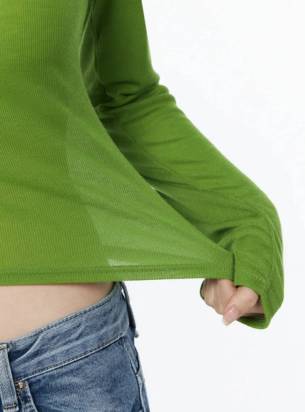 Sheer Slim Fit Long Sleeve Top IU525 Green close-up detail of ribbed fabric texture hem and flared sleeve cuff with thumbhole on model paired with low-rise jeans