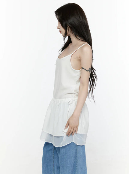 Sheer Strap Layered Dress IL521 White side view on model showing silhouette of peplum frill, drawstring waist tie, and translucent double-layer hem with wide-leg jeans